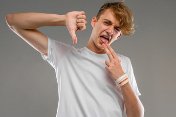 Young caucasian man in white t-shirt posing and gesticulating on camera isolated on grey background