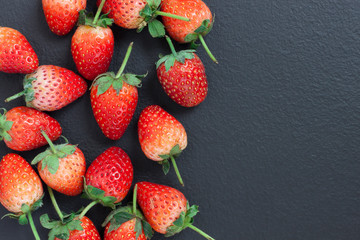 top view of a red strawberry placed on a black table with a copyspace