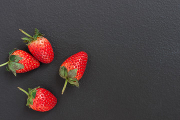 top view of a red strawberry placed on a black table with a copyspace