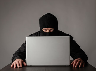 Hacker in mask using a laptop.