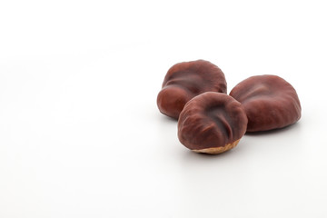 three isolated dried chestnuts resembling hearts on a white background