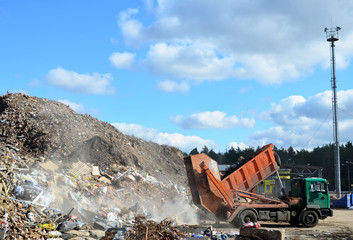 Garbage truck unloads construction waste from container at the landfill. Industrial waste treatment processing plant. Recycling waste concrete  and demolition material