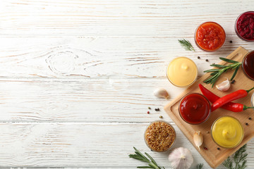 Naklejka na ściany i meble Tasty sauces in bowls, spices and board on wooden background, top view