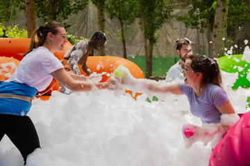 Adults collecting balls in inflatable pool with foam