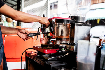 Barista makes the coffee by the coffee machine. Selective focus at the coffee machine.