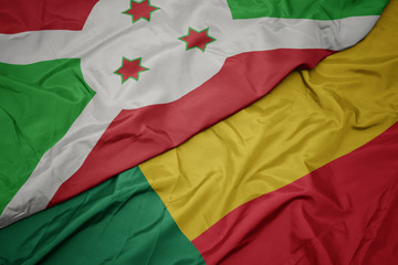waving colorful flag of benin and national flag of burundi .