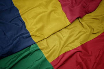 waving colorful flag of benin and national flag of chad.