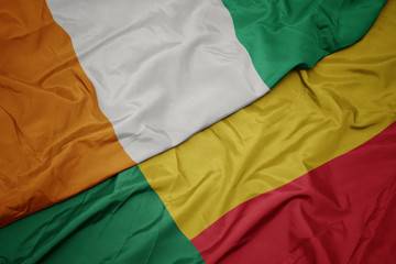 waving colorful flag of benin and national flag of cote divoire.