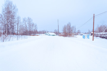 winter village  in the snow on a sunny day. street of wooden houses  road at houses near the forest, no people.