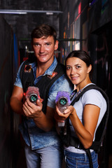 couple holding colored laser guns during laser tag game