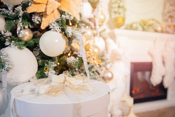 White boxes gifts on background of Christmas tree and fireplace, silver bow
