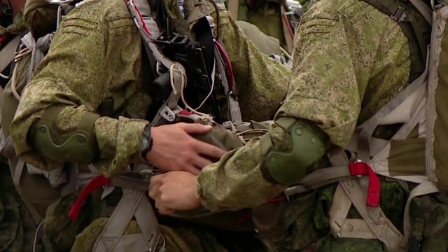 Military soldiers paratroopers check parachutes and equipment before jumping from an airplane