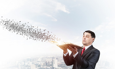 Serious businessman with open book looking up