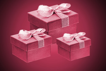 three dark red purple gift boxes on a red gradient background. close up