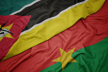 waving colorful flag of burkina faso and national flag of mozambique.