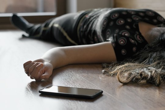 Woman lying on the floor at home, phone fallen near her hand.