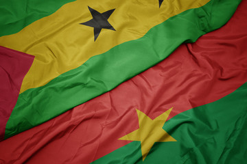waving colorful flag of burkina faso and national flag of sao tome and principe .