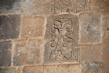 ancient khachkar on the wall of a basalt church. ancient stone carving. beautiful patterns on...
