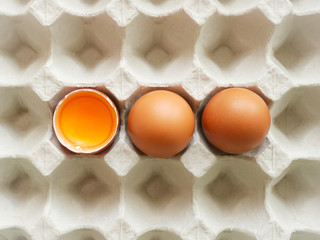 Concept healthy food, Fresh brown chicken eggs and yolk in eggshell on paper tray pattern background