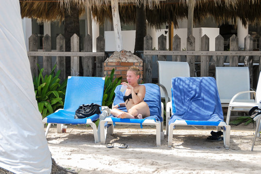 young woman sits in the chaise lounge on the edge of the sea. summer holidays and vacation - girl sunbathing on the beach chair. 