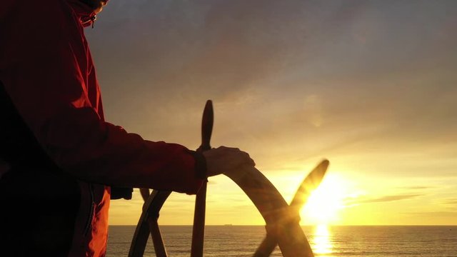 Man holding ship rudder in sunset light in sunset light.