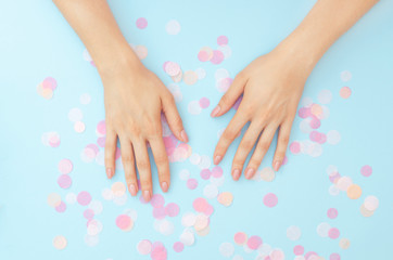 Female hands with a gentle nude manicure on a blue background.