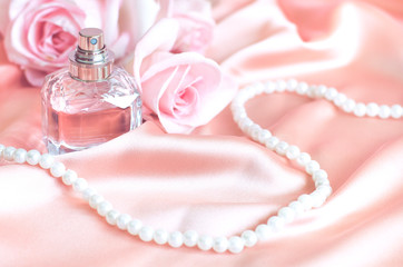Obraz na płótnie Canvas Female perfume bottle, rose, pearls on pink silk.