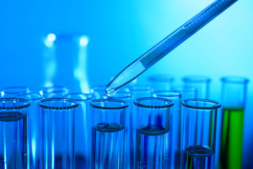 Pipette dropping sample into test tube blue light