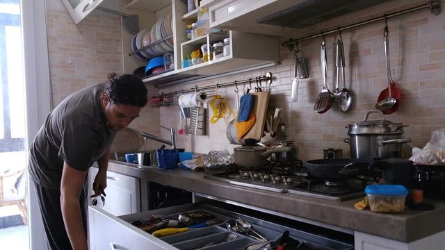 man housework chores do the dishes and put it in cutlery drawer