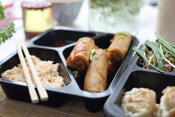 Spring roll fried in soy sauce and salad. Ready food from the store packed in a take-out box