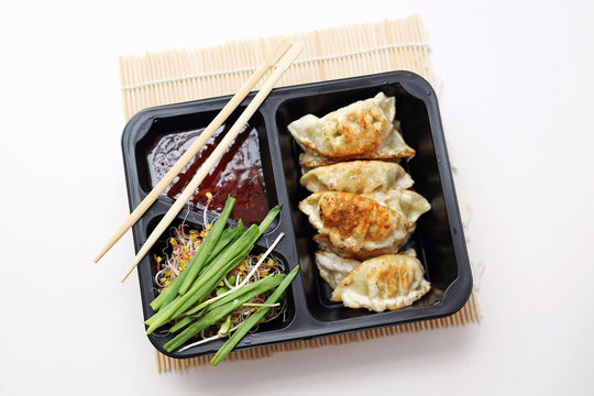Chinese dumplings with sweet-sour sauce and salad. Ready meal on a tray. Box diet, dietetic catering.