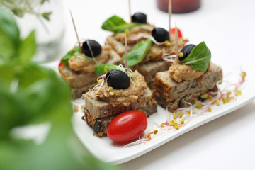 Party snack, mini sandwich with roasted meat, baked vegetable mousse and black olive.