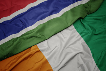 waving colorful flag of cote divoire and national flag of gambia.