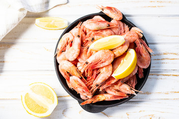 Fresh organic shrimps with lemons on vintage wooden table top view. Sea food concept.