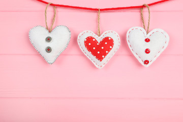 Fabric hearts with clothespins hanging on pink wooden background