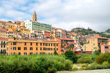 Fototapeta na wymiar Colorful residential buildings are stacked on a hillside underneath the Ventimiglia Cathedral in the seaside town of Ventimiglia, Italy.