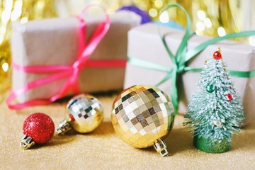 Two wrapped gift boxes with bow ribbon, green Christmas tree, red and golden balls. Beautiful New Year home decoration. Winter holidays atmosphere