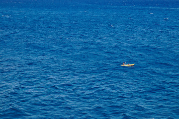 Fototapeta na wymiar Yellow boat with two unidentified people in the ocean