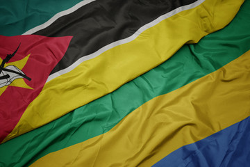 waving colorful flag of gabon and national flag of mozambique.