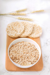 breakfast oatmeal on a wooden board next to crisp bread on a white background