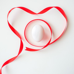 Healthy love food valentine day idea concept, Isolated gift of fresh duck egg with red heart symbol ribbon decorated on white table background-top view(selective egg soft focus)