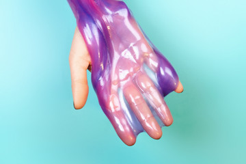 hands with holding slime in purple color on blue background