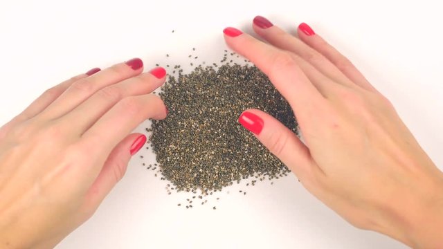 Closeup view pouring black chia seeds from glass jar and forming heart shape from it