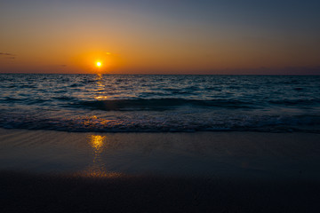 Obraz premium susnet over the ocean, the light is reflecting in the sea while the sun sets farway on the horizon 