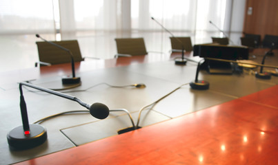 Fototapeta na wymiar microphone on a wooden table and empty chairs in a boardroom