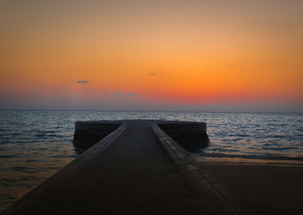 sunset at the pier in the Indian Ocean with a orange sky at the horizon 