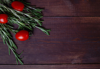 rosemary pepper and cherry tomatoes on dark wood background