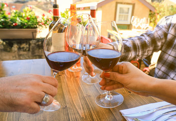 Hands holding glasses and toasting at festive party in a restaurant, celebration concept
