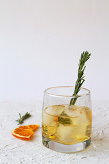 cold drinks. glass of lemonade or cocktail with pieces of ice and a sprig of rosemary on a white background. glass of whiskey with ice and slices of orange on white table.