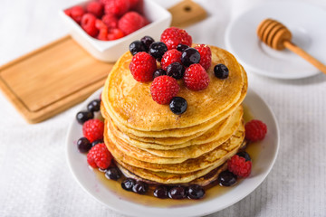 Sweet homemade pancakes with raspberries on white plate with fork.